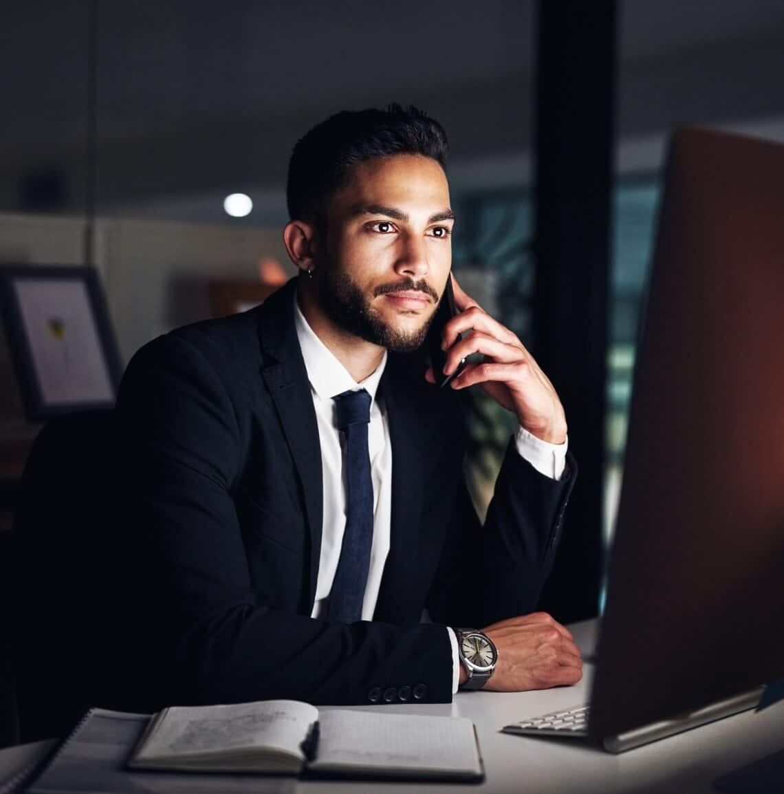 Man looking at his desktop while making a phone call