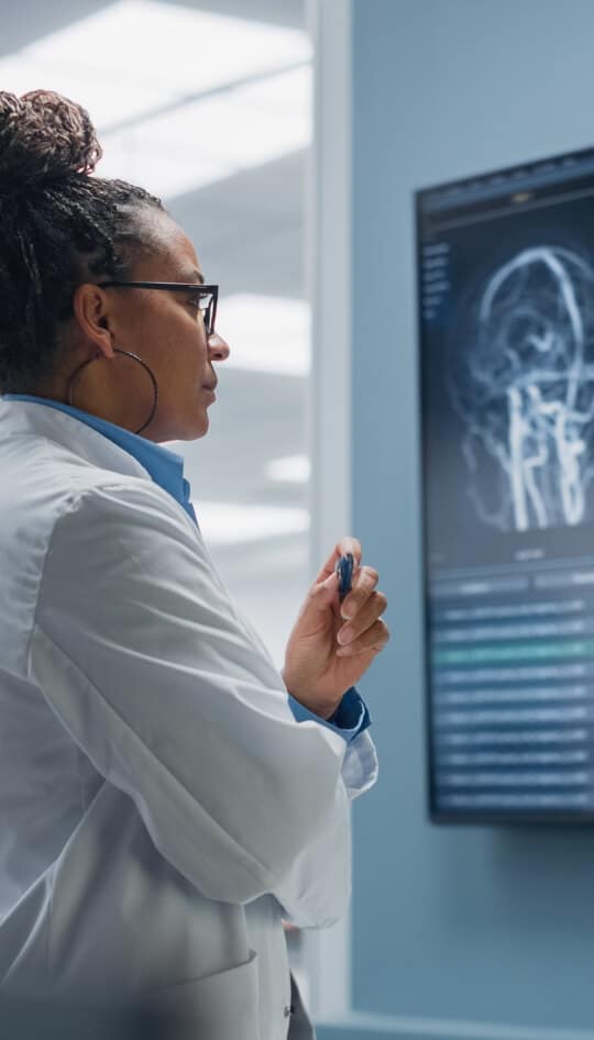 Female doctor studying brain scans on a wall screen