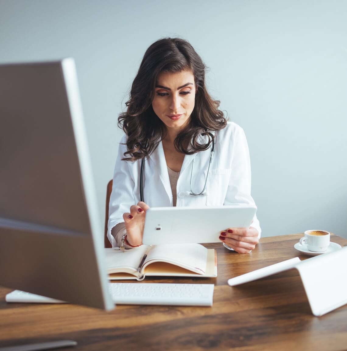 Female medical professional sitting at her desk using a tablet
