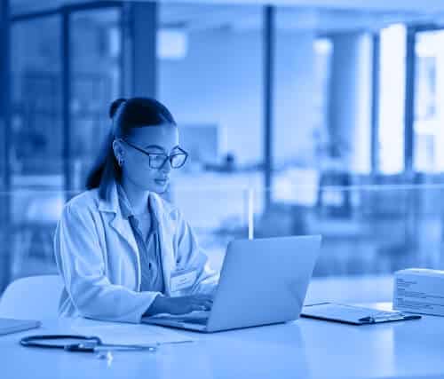 Doctor using a laptop at a desk in a hospital