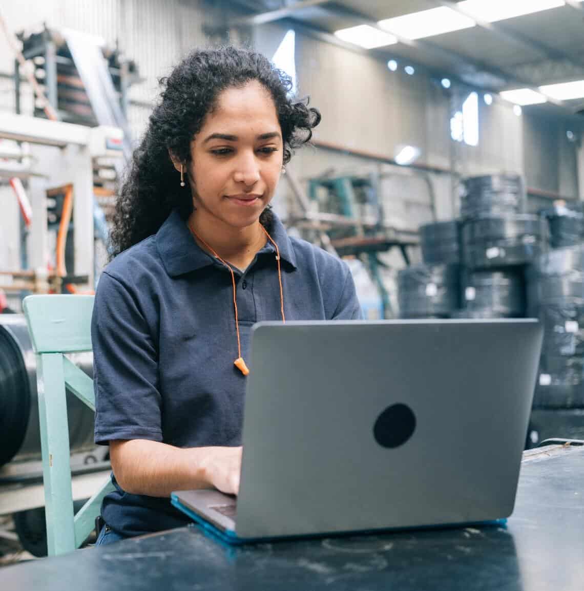 Woman working on a laptop in a warehouse