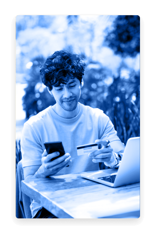 Man using his phone and a credit card at an outdoor table