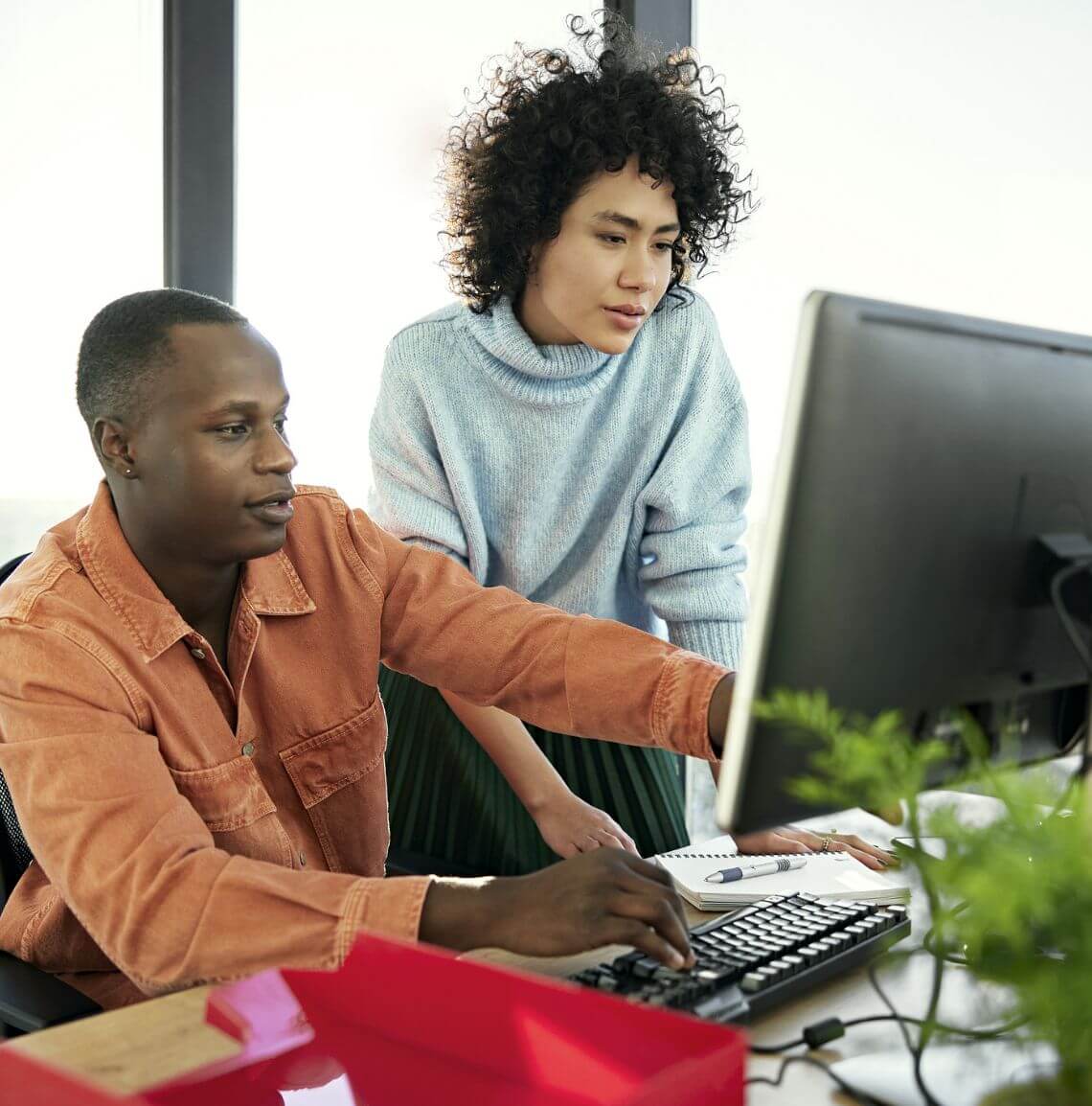 Two coworkers working on a desktop together