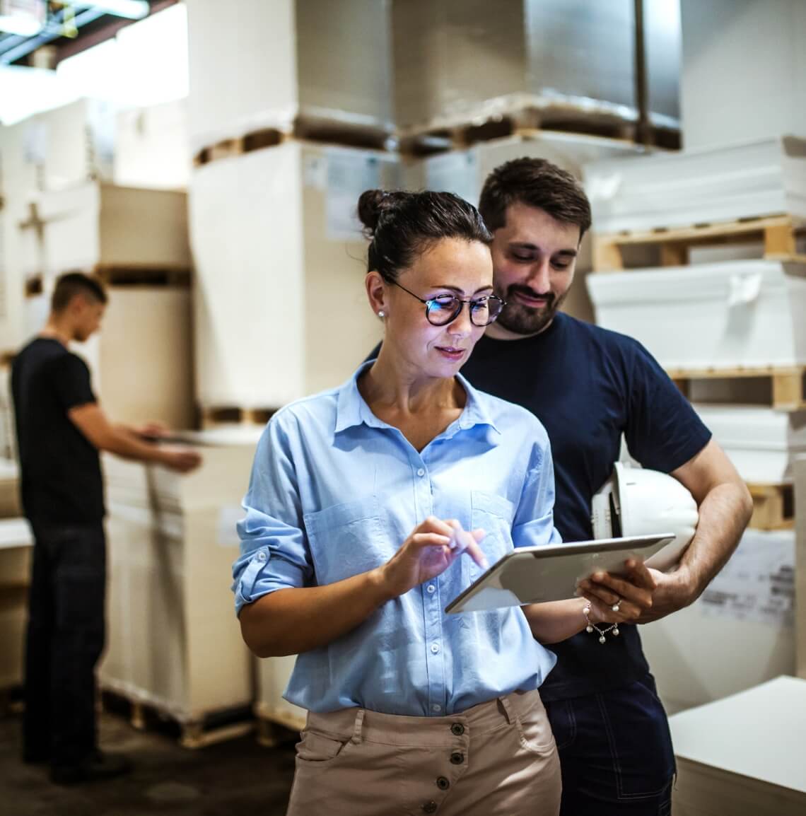 Two people using a tablet in a factory warehouse