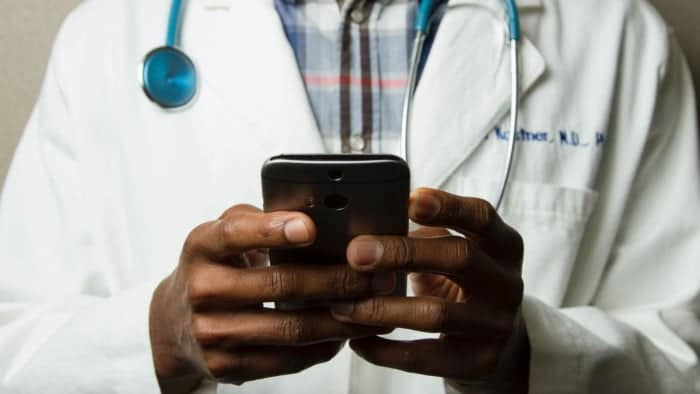Male medical professional holding a cell phone