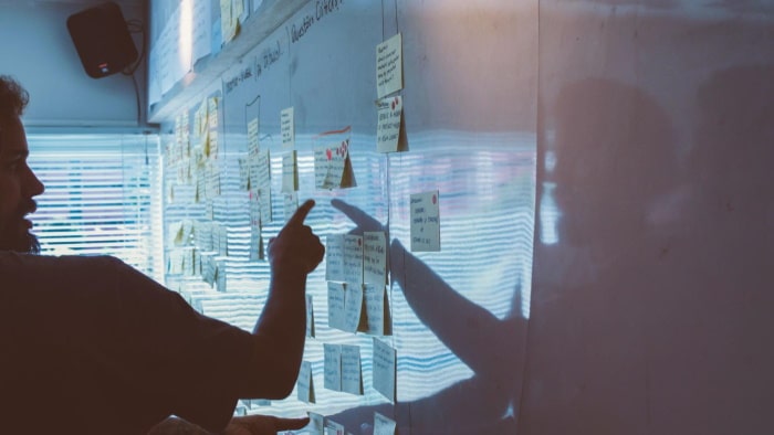 Two people pointing to sticky notes stuck up on the wall