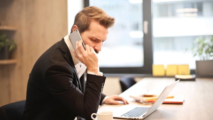 Man on the phone at work with a laptop in front of him