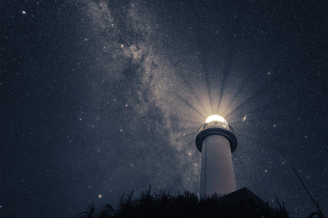 Night sky with stars and a bright lighthouse shining