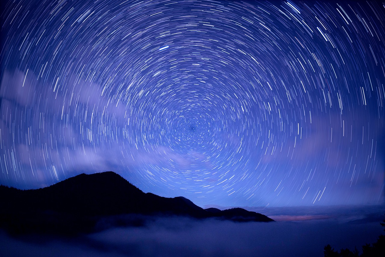 Blue night sky with black mountains and fog